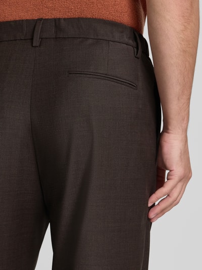 Männermodel trägt Bundfaltenhose mit Gesäßtaschen Modell 'MARYKO' von DRYKORN in Dunkelbraun, feine Textur, Nahaufnahme Rückansicht, Relaxed Fit, Knopf- und Reißverschluss, Kontext: Bundweite 28 cm, Innenbeinlänge 63 cm bei Größe 32/32.