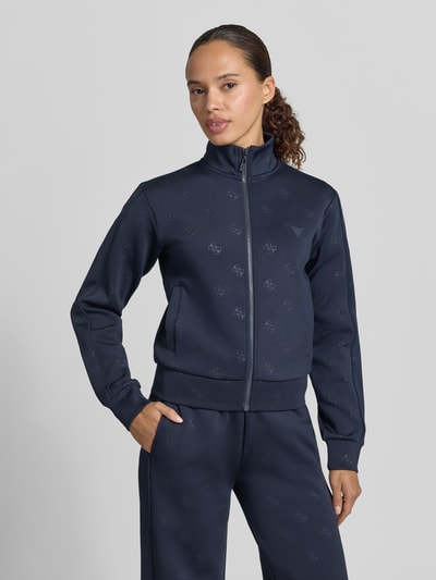 Frauenmodel trägt dunkelblaue Sweatjacke mit Logo-Muster Modell 'CALISTA' von Guess Activewear, Regular Fit, Nahaufnahme Oberkörper.