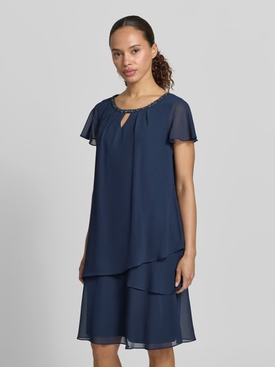 Frauenmodel trägt knielanges Cocktailkleid mit Schlüsselloch-Ausschnitt von Christian Berg Cocktail aus Chiffon im Stufen-Look mit Perlen, Gerader-Schnitt, dunkelblau, Ganzkörperansicht von vorne. Rückenlänge bei Größe 36: 93 cm, Brustweite: 47 cm, Ärmellänge: 12 cm.