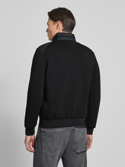 Männermodel trägt Jacke mit Label-Patch und Stehkragen von Antony Morato in Schwarz, strukturierte Oberfläche, Ganzkörperansicht Rückansicht. Kontext: Slim Fit, Zweiwege-Reißverschluss, seitliche Reißverschlusstaschen, elastische Abschlüsse, Rückenlänge 67 cm, Schulterbreite 48 cm, Brustweite 56 cm, Ärmellänge 67 cm.