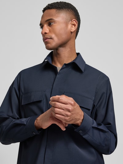 Männermodel trägt Relaxed Fit Hemdjacke mit Schurwoll-Anteil Model 'Arion' von DIGEL in Dunkelblau, Nahaufnahme Oberkörper, elastischer Material-Mix, Brusttaschen, Umlegekragen.