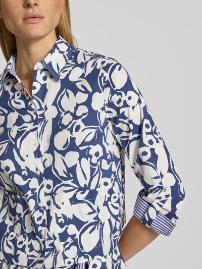 Modelka nosi Regular Fit Hemdbluse mit floralem Allover-Print von More & More, mieszanka bawełny elastyczna, krój regular fit, kwiatowy nadruk na całej powierzchni, kołnierzyk koszulowy, bluzka z długim rękawem, listwa guzikowa, długość tyłu w rozmiarze 36: 52 cm, długość rękawów w rozmiarze 36: 57 cm, widok z przodu, zbliżenie na górną część ciała.