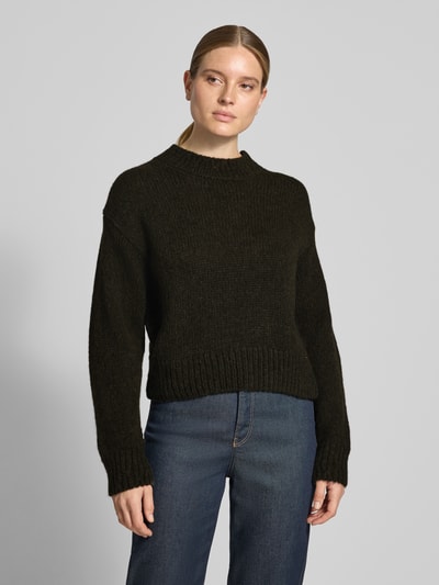 Frauenmodel trägt Relaxed Fit Strickpullover aus Woll-Alpaka-Mix von Marc Cain in Dunkelbraun, gerippte Abschlüsse, Ganzkörperansicht von vorne.