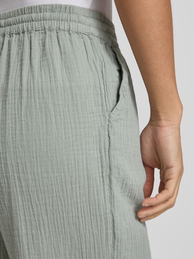 Männermodel trägt Relaxed Fit Weite Hose aus Bio-Baumwolle Modell 'THYRA' von Only, efekt: jednolity kolor, krepa, wpuszczane kieszenie, elastyczny ściągacz, zapięcie: tunel, wykończenie materiału: bawełna ekologiczna; detailaufnahme biodra i kieszeni