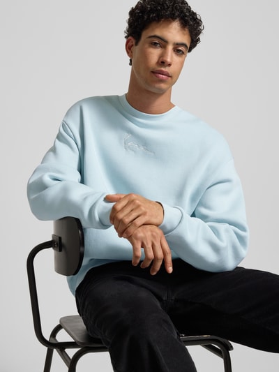 Männermodel trägt Sweatshirt mit Label-Stitching von KARL KANI aus Baumwoll-Mix in Hellblau, Lockerer Schnitt, Nahaufnahme Oberkörper.