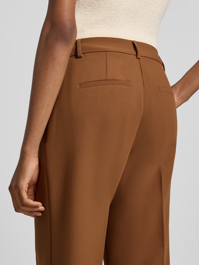 Frauenmodel trägt Straight Fit Hose mit Viskose-Anteil von Rich & Royal in Braun, glatte Textur, Gesäßtaschen, Detailaufnahme Rückansicht. Damen Hose, elastischer Viskose-Mix, Bügelfalten, Haken- und Reißverschluss, Bundweite 37 cm, Innenbeinlänge 70 cm.