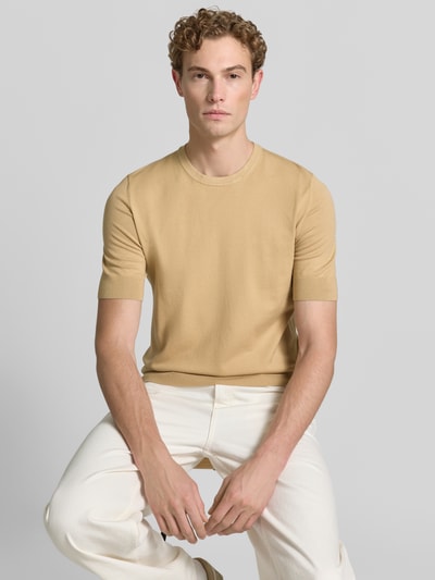 Męskimodel nosi Slim Fit T-Shirt aus Feinstrick Modell 'SAN CARL-CV' od HUGO, beżowy, gładka faktura, jasne spodnie, ujęcie z przodu, męski t-shirt