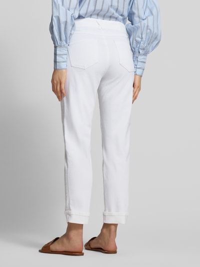Młody modelka nosi Slim Fit Jeans mit fixierten Beinabschlüssen Modell 'Darleen' von Angels, białe, 5-kieszeni, elastyczny materiał, szerokość w rozmiarze 36/30: 40 cm, długość nogawki 69 cm, krój slim fit, widok całej sylwetki z tyłu.