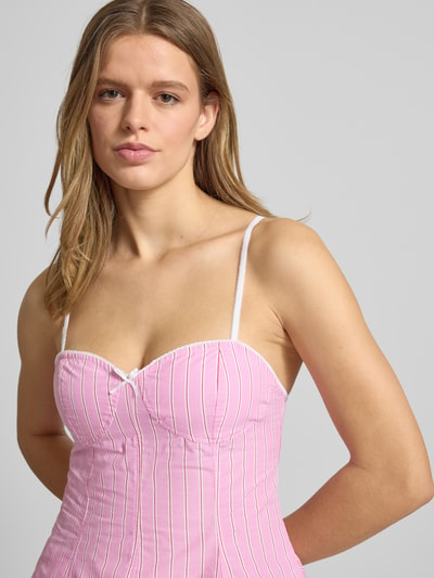 Frauenmodel trägt Slim Fit Top mit Zierschleife von Gina Tricot aus reiner Baumwolle, rosa mit weißen Streifen, Spaghettiträger, Nahaufnahme Oberkörper.