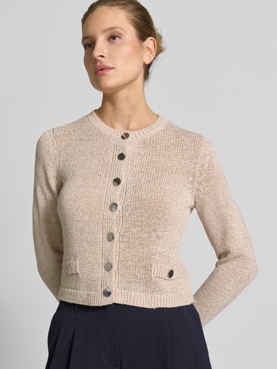 Frauenmodel trägt Strickjacke mit Rundhalsausschnitt und Knopfleiste von Betty Barclay, beige, grob gestrickte Textur, Nahaufnahme Oberkörper, Regular Fit, Ziertaschen, Rückenlänge 48 cm, Ärmellänge 61 cm.