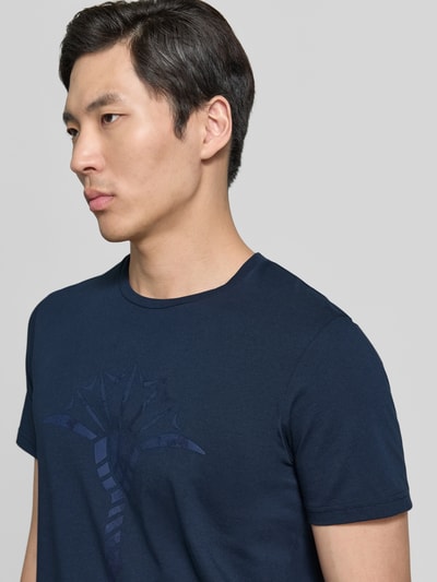 Männermodel trägt T-Shirt mit Rundhalsausschnitt Modell 'Alerio' von JOOP! Collection, Reine Baumwolle, Regular-Fit, Logo, Nahaufnahme Oberkörper.