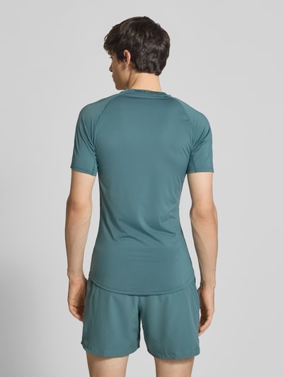 Männermodel trägt T-Shirt mit Logo-Print und Rundhalsausschnitt von NIKE TRAINING in Slim Fit, Raglanärmel, Rückansicht, Ganzkörperansicht.