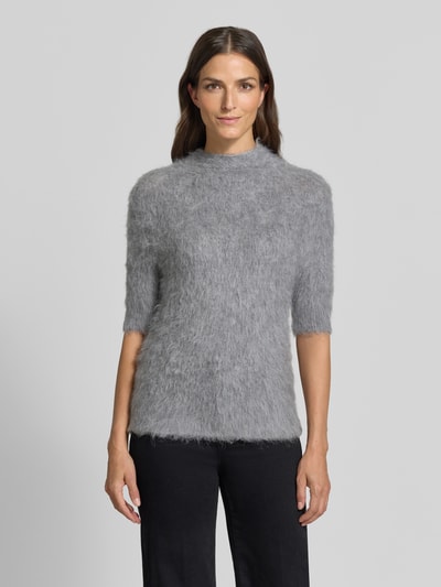 Frauenmodel trägt Strickshirt aus Alpaka-Mix mit kurzem Stehkragen von someday, grau meliert, feine flauschige Textur, körpernaher Schnitt, Halbarm, Ganzkörperansicht von vorne.