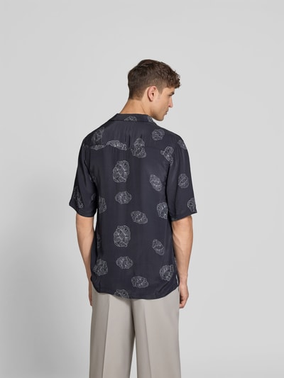 Männermodel trägt Relaxed Fit Langarmbluse aus Viskose von Officine Générale, dunkles Muster, Reverskragen, Ganzkörperansicht Rückansicht. Kontext: Herren Langarmbluse, Reine Viskose, Relaxed-Fit, Reverskragen, Durchgehende Knopfleiste, 3/4-Arm, Rückenlänge bei Größe M 80 cm, Schulterbreite bei Größe M 47 cm, Ärmellänge bei Größe M 33 cm.