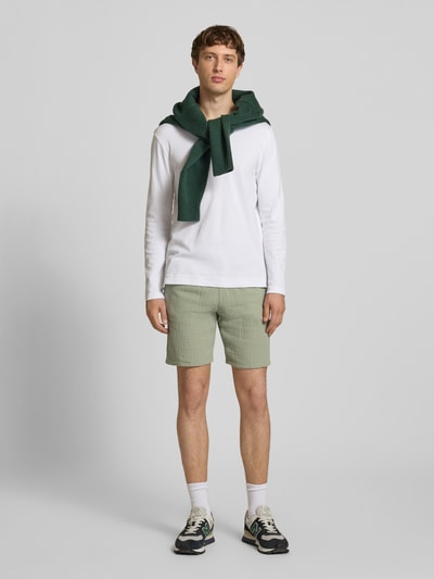Mannelijk model draagt shorts met structuurpatroon model 'AIDEN' van Jack & Jones, materiaalmix met katoen, straight fit, elastische band met trekkoord, zijsteekzakken, groene tint, bandwijdte maat M 40 cm, binnenbeenlengte 21 cm, geheel van voren gefotografeerd.