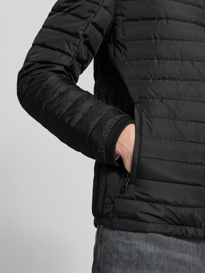 Männermodel trägt Regular Fit Jacke in Stepp-Optik Modell 'OLYMPUS' von NAUTGÅRD in Schwarz, Nahaufnahme Oberkörper, glatte Struktur, seitliche Tasche sichtbar.