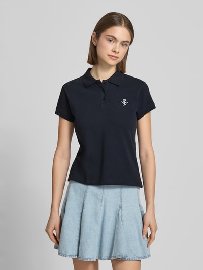 Vrouwenmodel draagt kortärmliges Poloshirt in Piquéoptik mit Kragen und Logostickerei van REVIEW, effen donkerblauw, slim fit katoen, piquéstructuur, polokraag, korte mouwen, logoborduur, ruglengte circa 52 cm, vooraanzicht bovenlichaam.