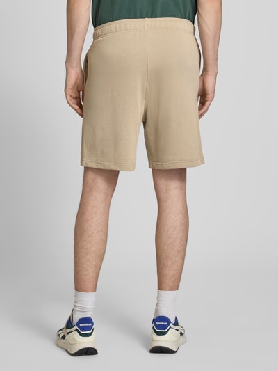 Mannelijk model draagt Shorts mit elastischem Bund und Label-Stitching van CHAMPION in beige, katoenmix, regular fit, elastische tailleband, label-stitching detail, bandwijdte maat M 43 cm, binnenbeenlengte maat M 17 cm, volledige lichaamsachteraanzicht