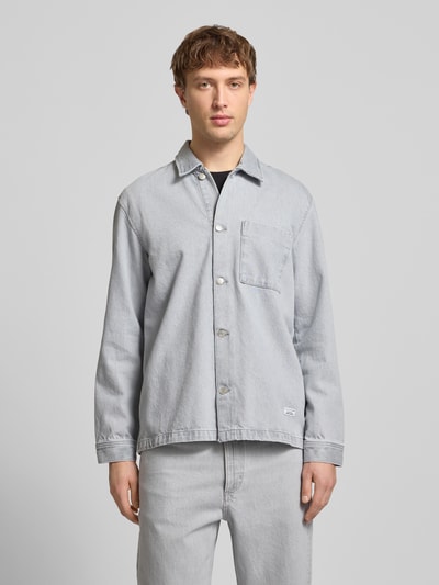 Männermodel trägt Regular Fit Hemdjacke aus reiner Baumwolle von Marc O'Polo Denim in Denim-Optik, Umlegekragen, Langarm, Brusttasche, einreihige Knopfleiste, Label-Patch, helle Farbgebung, glatte Textur, Ganzkörperansicht von vorne.