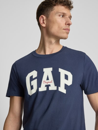 Männermodel trägt T-Shirt mit Logo und Rundhalsausschnitt von GAP in Dunkelblau, Reine Baumwolle, Regular-Fit, Nahaufnahme Oberkörper.