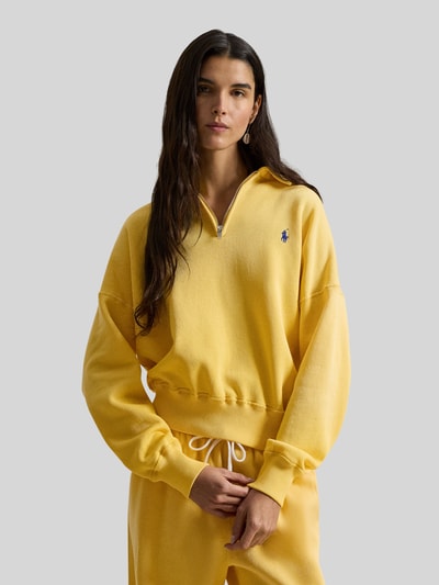 Vrouwenmodel draagt Sweatshirt met Label-Stitching van Polo Ralph Lauren in geel, polokraag, korte rits, geribde boorden, katoenmix, losse snit. Vooraanzicht bovenlichaam.