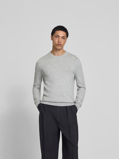 Männermodel trägt Slim Fit Pullover aus Woll-Mix von Filippa K, hellgrau, Strick-Optik, Rundhalsausschnitt, Ganzkörperansicht von vorne.