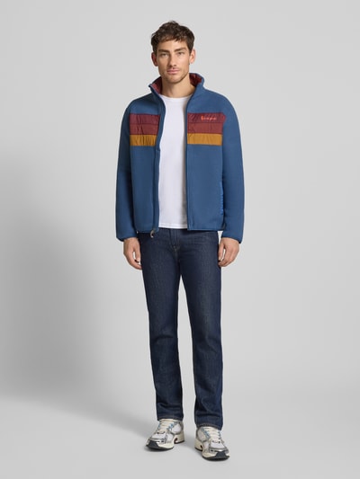 Männermodel trägt Jacke mit Stehkragen Modell 'Teca' von Cotopaxi, Regular-Fit, Label-Print, Reißverschluss, Eingrifftaschen, Ganzkörperansicht von vorne.