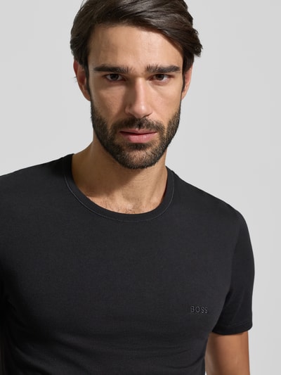 Männermodel trägt T-Shirt mit Label-Stitching im 3er-Pack Modell 'Classic' von BOSS in Schwarz, reine Baumwolle, Nahaufnahme Oberkörper.