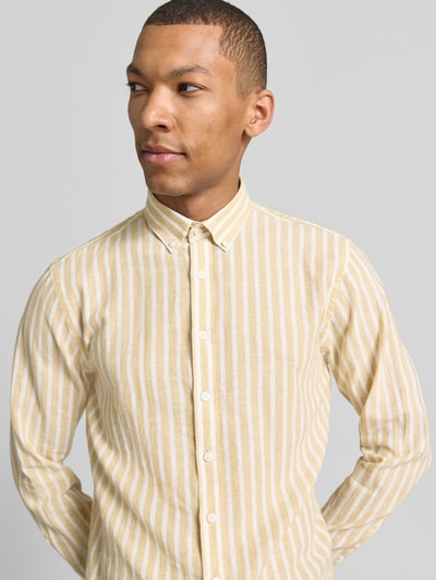 Męski model nosi Relaxed Fit Freizeithemd mit Button-Down-Kragen od Lindbergh, len z bawełną, paski, jasny żółty, zapięcie na guziki, szerokość w rozmiarze M: 41 cm, długość tyłu: 64 cm, długość rękawa: 64 cm, widok z przodu, zbliżenie na górną część ciała.