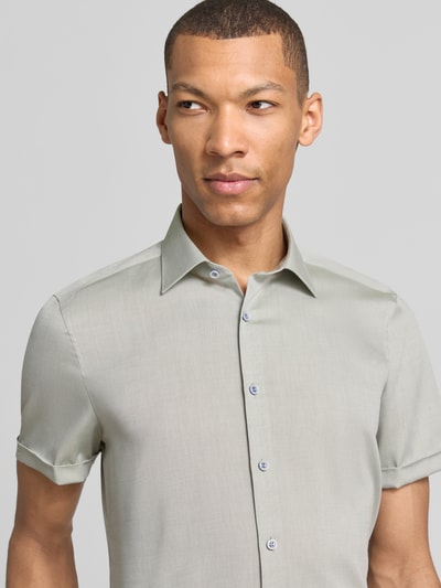 Męski model nosi Slim Fit Business-Hemd mit Kentkragen od OLYMP Level Five, jasnoszary, gładka bawełna, krój slim fit, krótki rękaw z mankietem, zapięcie na guziki, Szerokość w rozmiarze 40: 40 cm, długość pleców: 70 cm, długość rękawa: 24 cm, półzbliżenie przód.