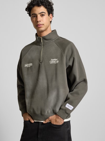 Männermodel trägt Sweatshirt mit Stehkragen von ANOTHER COTTON LAB, Baumwoll-Mix, lockerem Schnitt, Label-Details, Nahaufnahme Oberkörper.
