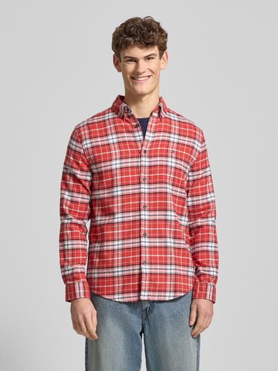 Männermodel draagt Regular Fit Flanellhemd aus reiner Baumwolle van Tommy Jeans, rood-wit ruitpatroon, lange mouwen, voorkant, ganzkörperansicht von vorne.