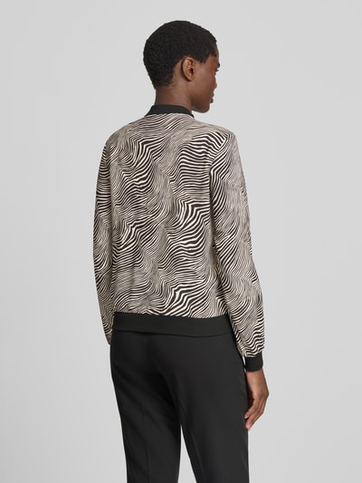 Frauenmodel trägt Regular Fit Blouson mit Allover-Muster Modell 'COCO' von VERO MODA, abstraktes schwarz-weiß Muster, Ganzkörperansicht Rückansicht. Damen Bomberjacke / Blouson.