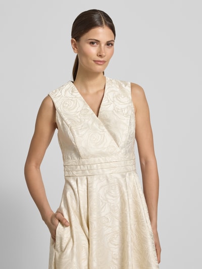 Frauenmodel trägt Regular Fit Midikleid mit floralem Allover-Stitching von Rinascimento in Creme mit Wickel-Optik, Nahaufnahme Oberkörper.