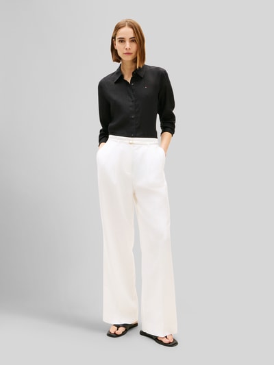 Frauenmodel trägt Relaxed Fit Langarmbluse aus reinem Leinen von Tommy Hilfiger, Optik: Unifarben, Passform: Relaxed-Fit, Hemdkragen, Logo-Stitching, Knopfleiste, Ärmelform: Langarm, Ärmelabschluss: Manschette, Rumpfabschluss: abgerundet, Materialverarbeitung: Flammgarn, Material: Leinen, Farbe: schwarz, glatte Textur, Ganzkörperansicht von vorne.