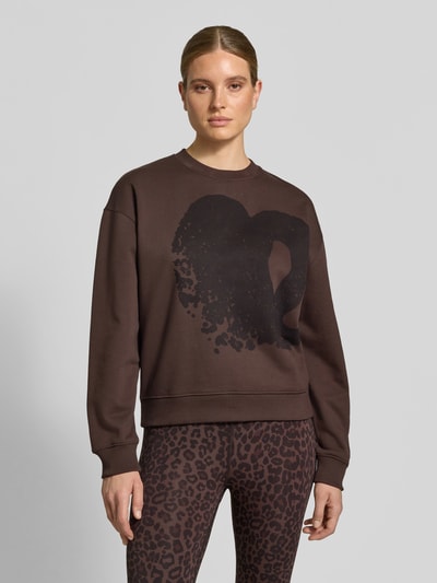 Vrouwenmodel draagt Oversized Sweatshirt uit katoen van Lala Berlin, donkerbruin, ronde hals, ribboorden, printmotief, maat S ruglengte 60 cm, voorkant volledige lichaamsweergave.