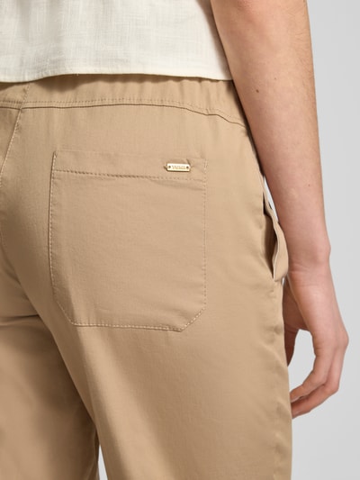 Kobieta nosi Chino mit elastischem Bund Modell 'Sue' od TONI, bawełniany miks z domieszką stretchu, szeroki krój, beżowy, detal tylnej kieszeni, zbliżenie okolicy bioder