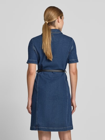 Frauenmodel trägt Knielanges Jeanskleid mit Gürtel von Marc Cain aus Baumwoll-Lyocell-Anteil, Taillierter Schnitt, Knielänge, Hemdblusenkragen, Knopfleiste, Gürtel, Rückenlänge 96 cm, Brustweite 42 cm, Ärmellänge 25 cm, dunkelblauer Denim, glatte Struktur, Ganzkörperansicht Rückansicht.