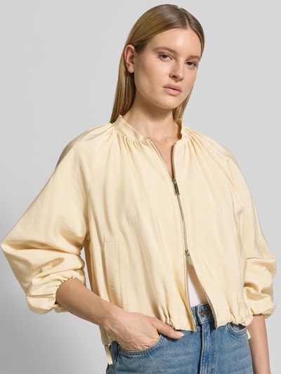 Frauenmodel trägt Regular Fit Jacke aus Viskose-Mix Modell 'Fico' von Marella in hellem Gelb mit Zweiwege-Reißverschluss, elastische Abschlüsse, Falten-Optik, Nahaufnahme Oberkörper. Rückenlänge bei Größe 36: 52 cm, Schulterbreite: 42 cm, Brustweite: 53 cm, Ärmellänge: 55 cm.