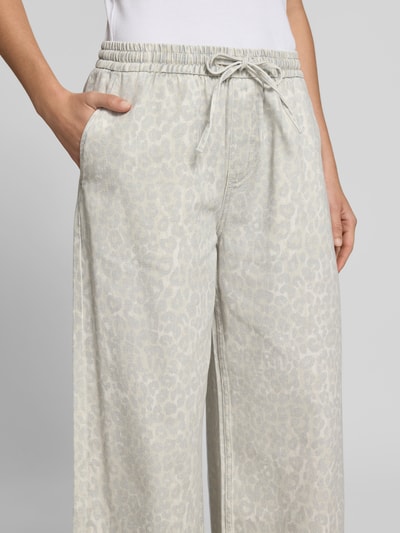 Frauenmodel trägt Stoffhose mit Allover-Animal-Print von Lala Berlin aus Reiner Baumwolle, Wide-Fit, elastischer Bund mit Tunnelzug, seitliche Eingriffstaschen, dezente graue Musterstruktur, Nahaufnahme Oberkörper.