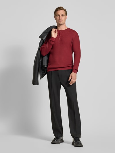 Männermodel trägt Strickpullover aus Lyocell-Woll-Mix mit Knopfleiste von Antony Morato in Ripp-Optik, Slim Fit, Ganzkörperansicht von vorne.