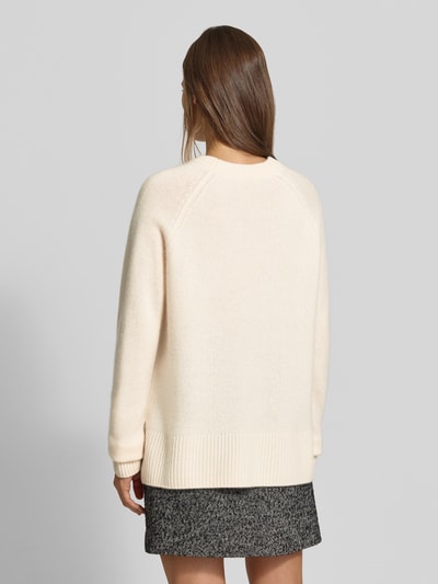Frauenmodel trägt Regular Fit Pullover aus reinem Kaschmir in Strick-Optik von MYON, cremefarben, kombiniert mit grauem Rock, Damenpullover mit Rundhalsausschnitt, Rückenlänge 68 cm, Ärmellänge 66 cm, Ganzkörperansicht Rückansicht.