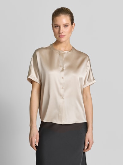 Kobiece modelka nosi Relaxed Fit Seidenbluse mit Rundhalsausschnitt od HERZENS, jedwabny elastyczny materiał, krótki rękaw, jasny beż, długość tyłu 63 cm, długość rękawa 18 cm, widok całej sylwetki z przodu.