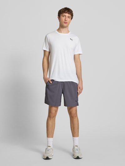 Männermodel trägt Shorts mit Logo und elastischem Bund von PUMA PERFORMANCE, Regular Fit, Grau, glatte Textur, Ganzkörperansicht von vorne.