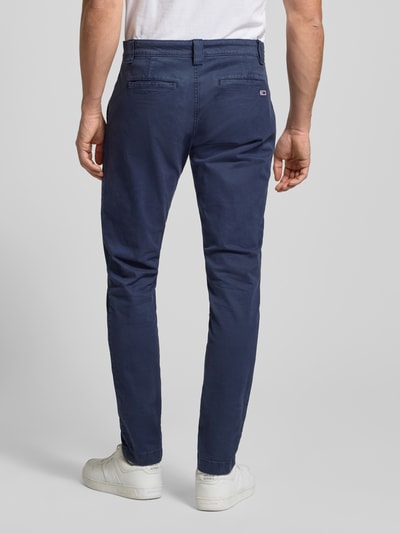 Männermodel trägt Regular Fit Chino aus Baumwoll-Mix Modell 'SCANTON' von Tommy Jeans, Unifarben, Ganzkörperansicht Rückansicht. Bundweite 40 cm, Innenbeinlänge 80 cm, Eingrifftaschen vorn, Knopf- und Reißverschluss.