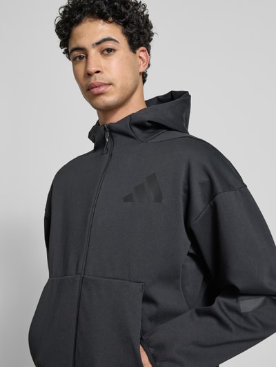 Männermodel trägt Sweatjacke mit Kapuze von adidas Sportswear, Material-Mix mit Baumwoll-Anteil, Regular Fit, Nahaufnahme Oberkörper.