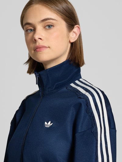 Frauenmodel trägt Oversized Sweatjacke aus Baumwoll-Mix Modell 'LACE OVERSIZED' von adidas Originals in Dunkelblau mit weißen Details, Nahaufnahme Oberkörper. Damen Sweatjacke von adidas Originals