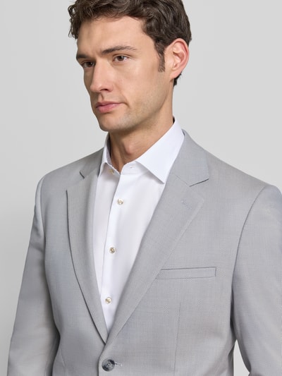 Mannelijk model draagt Super Slim Fit Anzugsakko met Woll-Anteil Model 'ARTI253X' van HUGO met all-over motief, reverskraag, 2-knoopsluiting, paspelzak op de borst, klepzakken, decoratieve knopen aan de mouw, dubbele rugsplit, kleur lichtgrijs, textuur fijn geweven, look formeel. Nahaufnahme bovenlichaam.