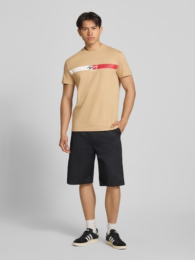 Männermodel trägt Regular Fit T-Shirt aus reiner Baumwolle von Tommy Jeans in Optik: Unifarben, Label-Print, Rundhals, Kurzarm, Jersey, Ganzkörperansicht von vorne.
