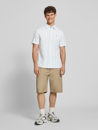 Männermodel trägt Regular Fit Freizeithemd aus Baumwoll-Mix von Tommy Jeans in Optik:Allover-Muster, gestreift, Ganzkörperansicht von vorne.